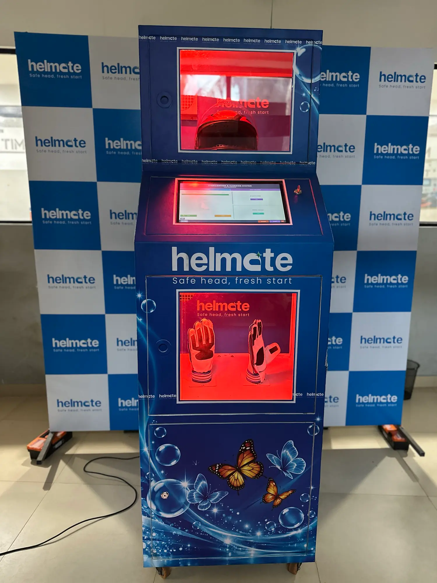 The Helmate helmet cleaning machine standing against a branded backdrop