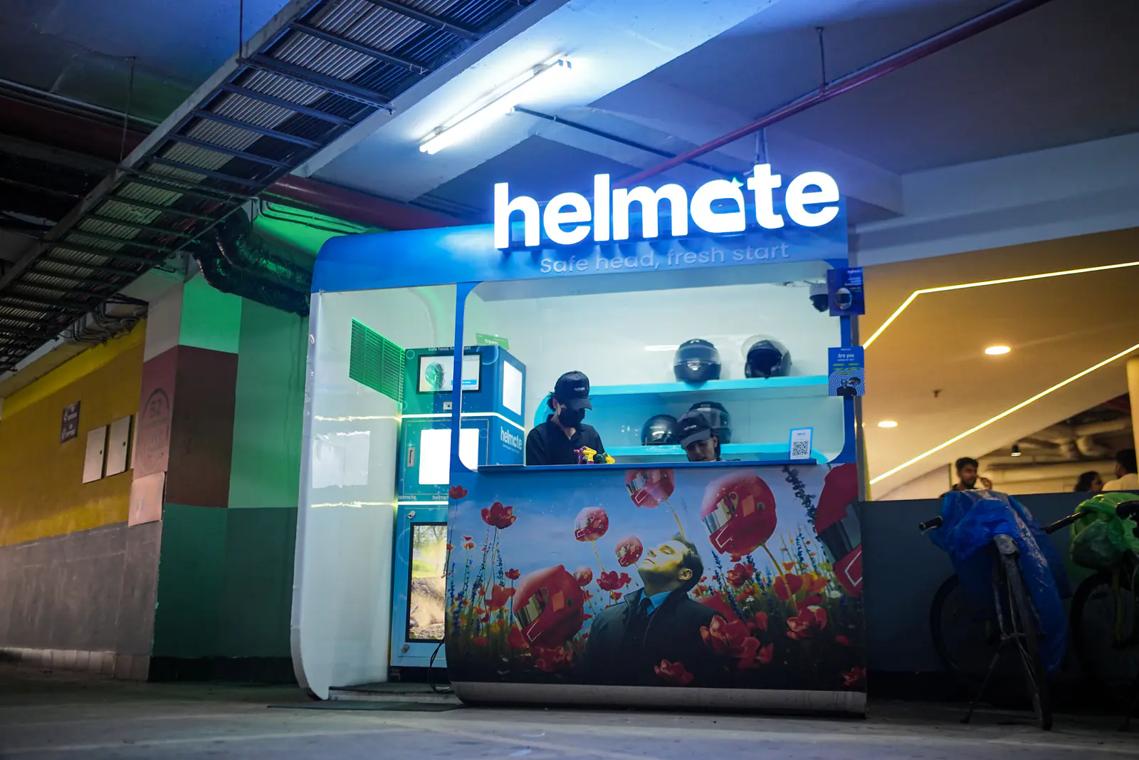 Helmate's illuminated storefront in the mall parking level at night