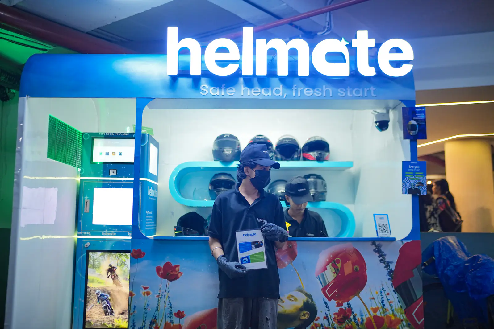 The Helmate kiosk lit up inside Hilite Mall, Calicut, with the crew at the counter