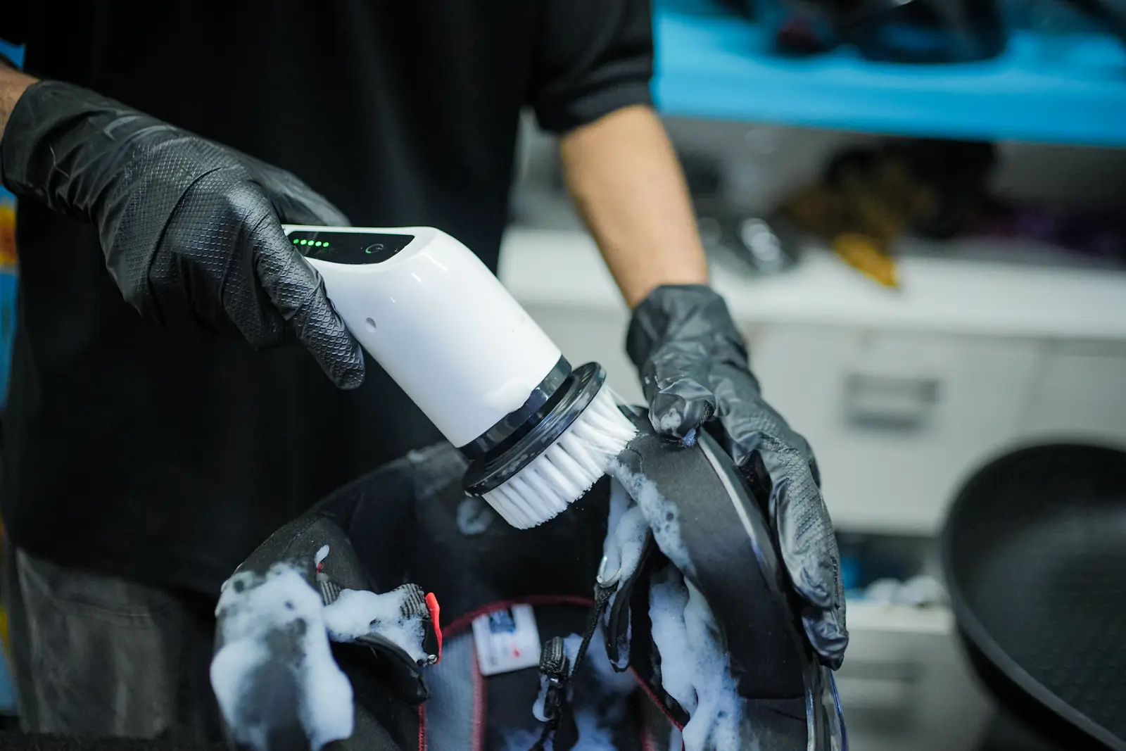 An electric detailing brush working cleaning foam through a helmet liner