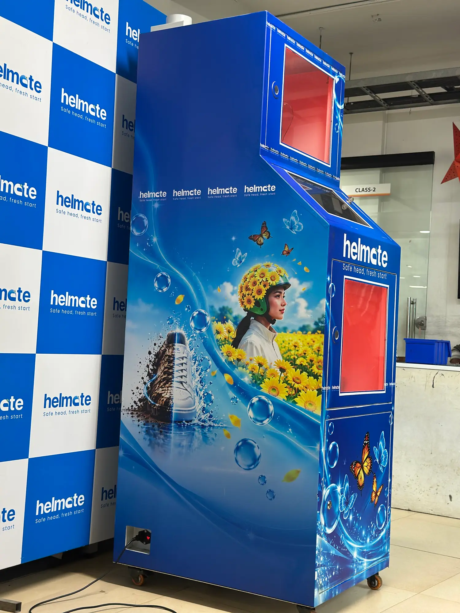 A side profile of the full-size Helmate unit against the branded backdrop
